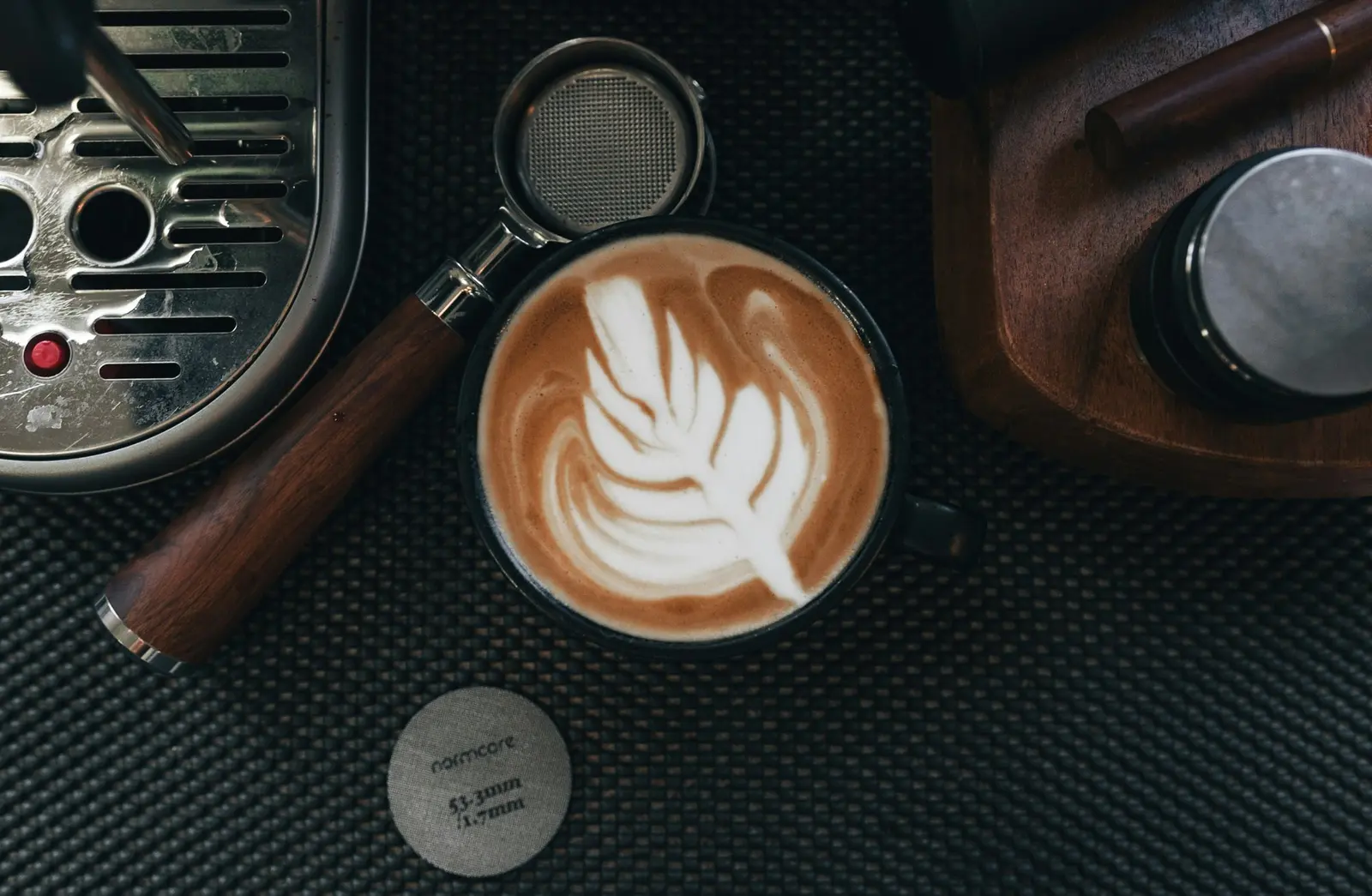 Cappuccino with latte art beside a portafilter