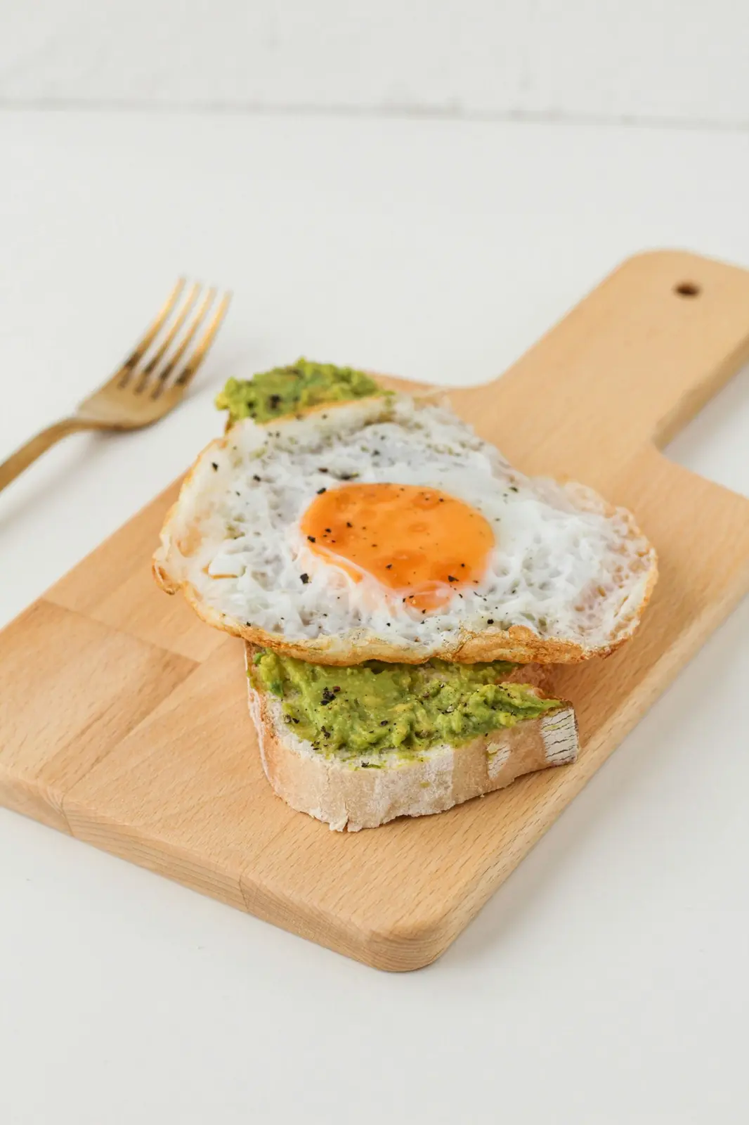Avocado toast with a fried egg on a wooden board