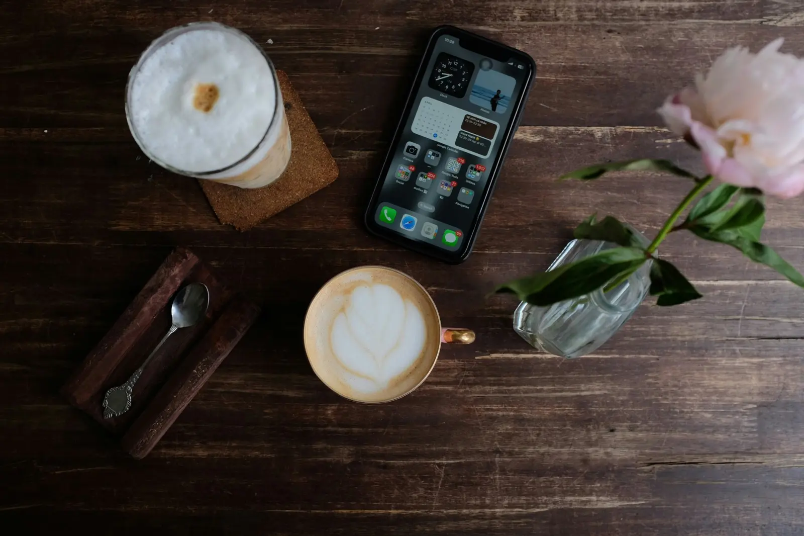 Coffee, a phone and a flower on a wooden cafe table