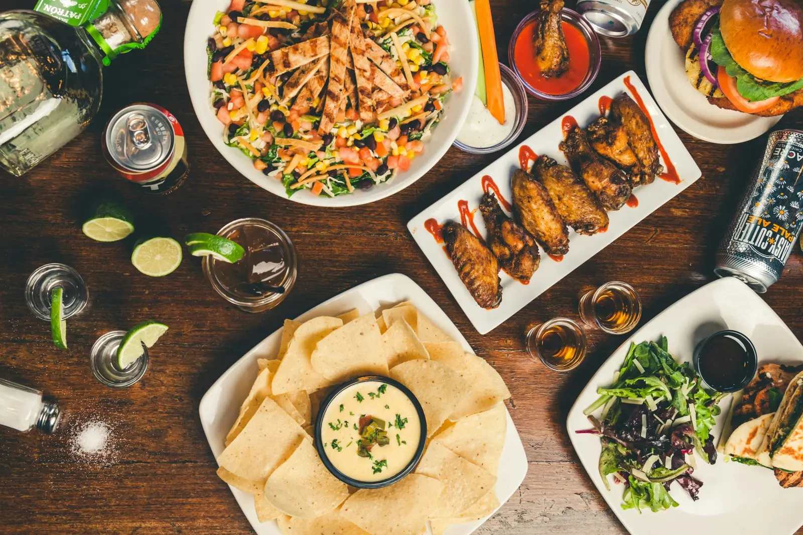 Table spread with wings, chips and salads seen from above
